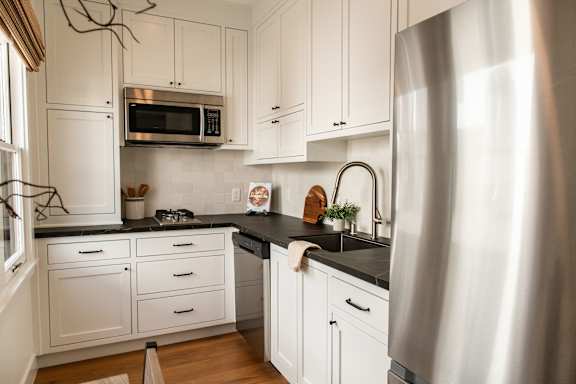 A modern kitchen with white cabinets and a stainless steel refrigerator.