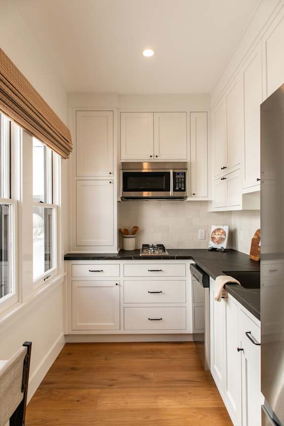 A kitchen with white cabinets and a black countertop.
