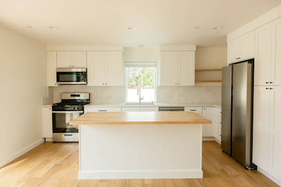 A kitchen with white cabinets and a wooden island.