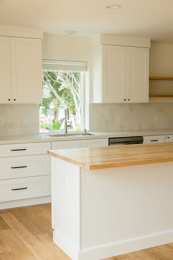 A kitchen with white cabinets and a wooden counter.