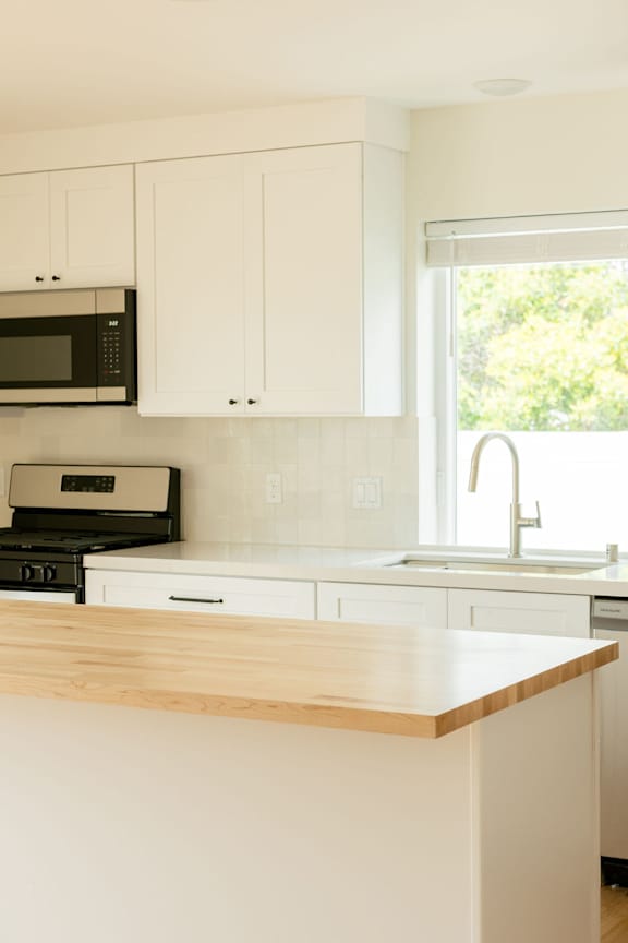 A kitchen with a microwave, oven, and sink.
