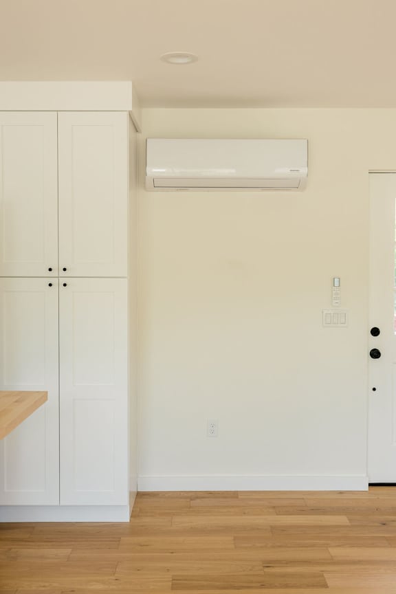 A white wall with a door and a cabinet.