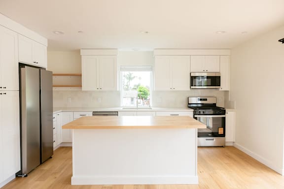 A kitchen with white cabinets and a wooden island.