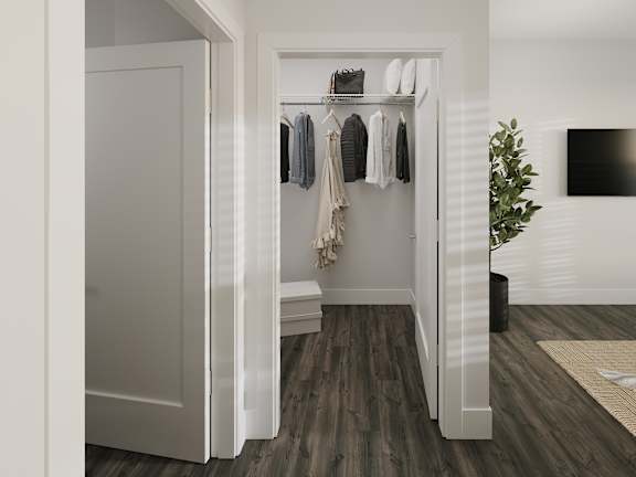 a walk in closet with a door to it and a wardrobe with clothes on it