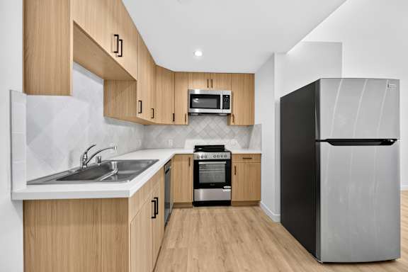 A modern kitchen with wooden cabinets and a black refrigerator.
