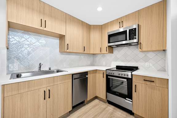 A kitchen with wooden cabinets and a stainless steel dishwasher.