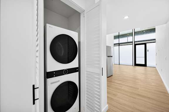A modern laundry room with a washer and dryer built into the cabinetry.