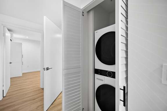 A white door is open to reveal a black washing machine inside.