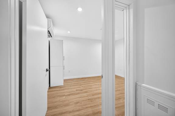 A white room with a wooden floor and a white door.