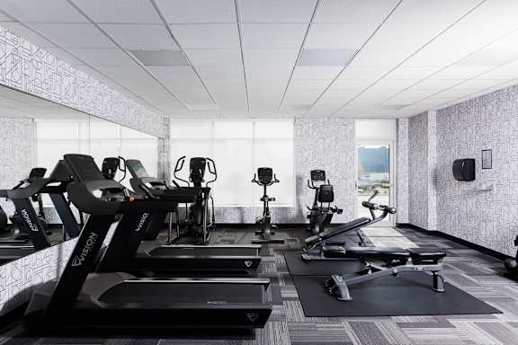 A row of treadmills and exercise bikes in a gym at 1600 Hyde Park Village Apartments, London
