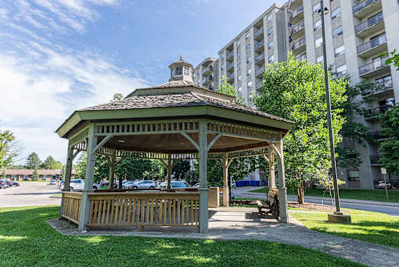 A gazebo with a brown roof is surrounded by a grassy area.