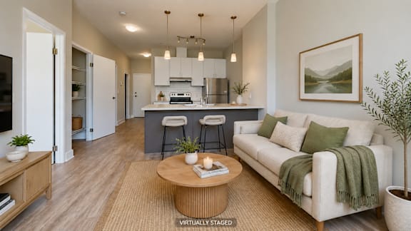 A modern living room with a sofa, coffee table, and kitchen area in the background.
