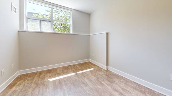 A room with light wood flooring and a window.