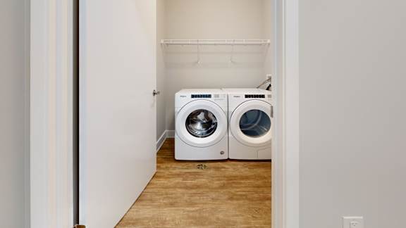 Two washing machines are placed in a small laundry room.