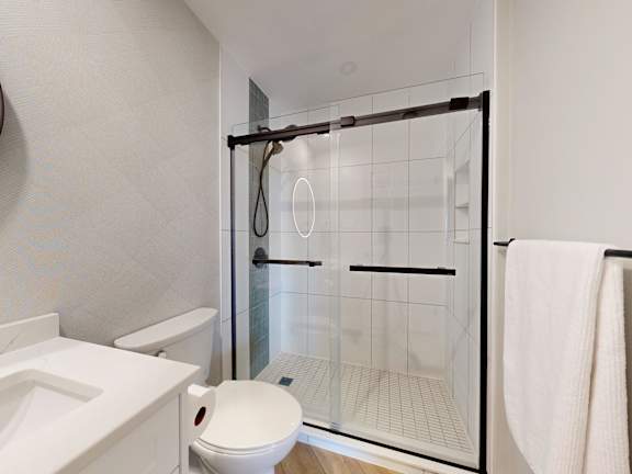 A white toilet sits next to a walk-in shower with a glass door.