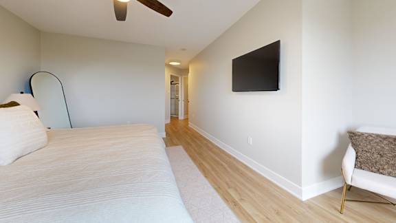 A bedroom with a bed, a chair, and a ceiling fan.