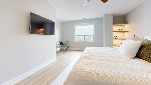 A bedroom with a large bed and a flat screen TV mounted on the wall.