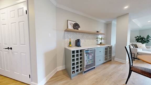 A grey cabinet with a wine rack is in a room with a white door.