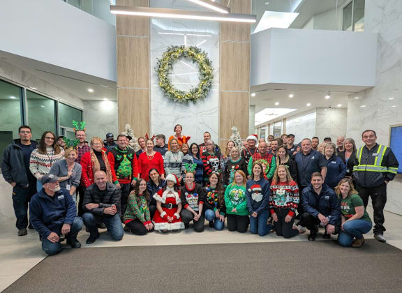 a group of people posing for a photo in front of a christmas wreath