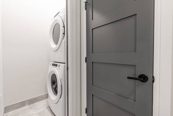 A washing machine is in a laundry room at 1600 Hyde Park Village Apartments, London