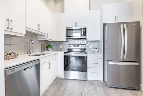 A modern kitchen with white cabinets and stainless steel appliances.