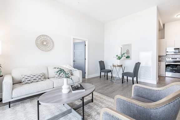 A living room with a white couch, grey armchairs, and a coffee table at 1600 Hyde Park Village Apartments, London