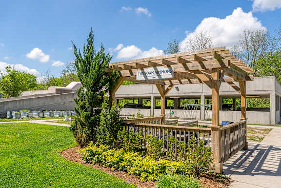 A wooden pergola with the name "Ethan Sinn" on it is surrounded by greenery.