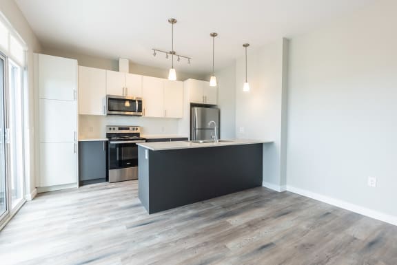 an empty kitchen with white cabinets and a black counter top