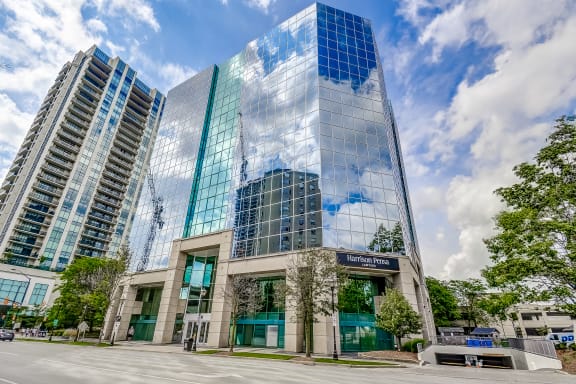 a large glass building with a blue sky and clouds reflected in it