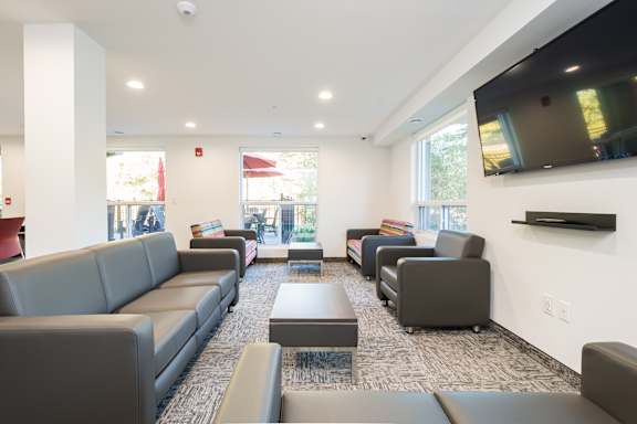 A living room with grey couches and a television on the wall.