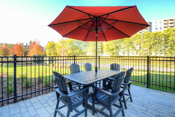 A table with chairs and an umbrella on a patio.