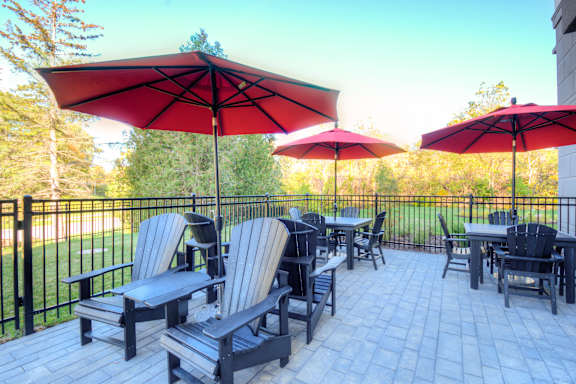 A patio with red umbrellas and chairs.