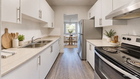 A modern kitchen with white cabinets and stainless steel appliances.