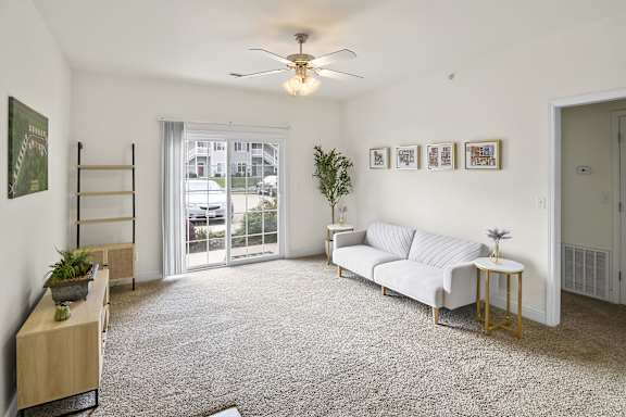 A living room with a white couch, a small table, and a ceiling fan.