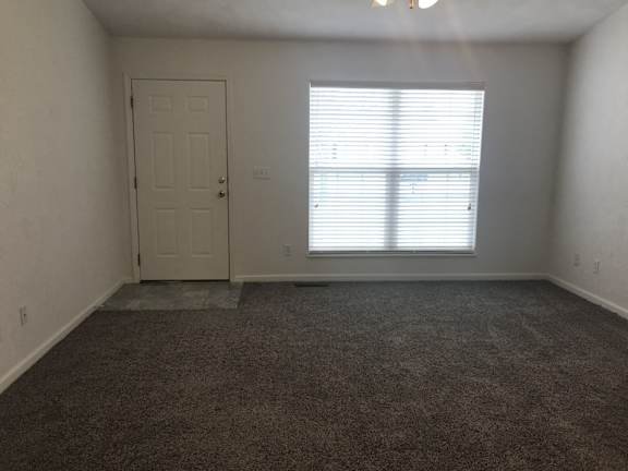 A room with a door and a window with blinds.
