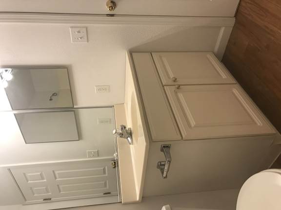 A white toilet is in a small bathroom with a cabinet and a mirror.