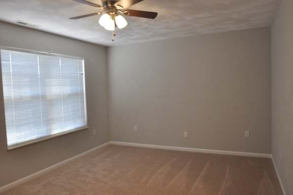 A room with a ceiling fan and a window with blinds.
