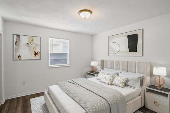 A bedroom with a large bed, two nightstands, and two framed pictures on the wall.