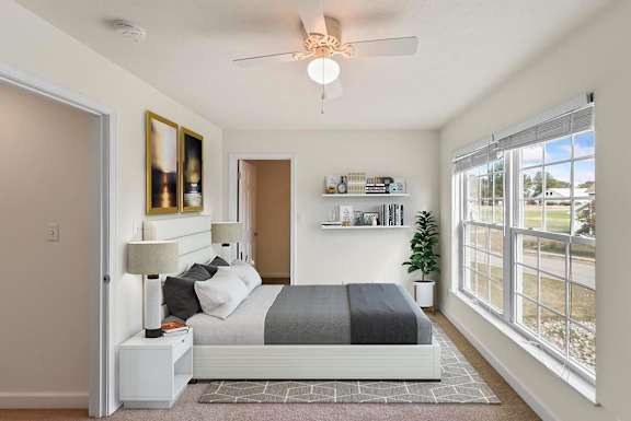 A bedroom with a bed, nightstand, and a ceiling fan.