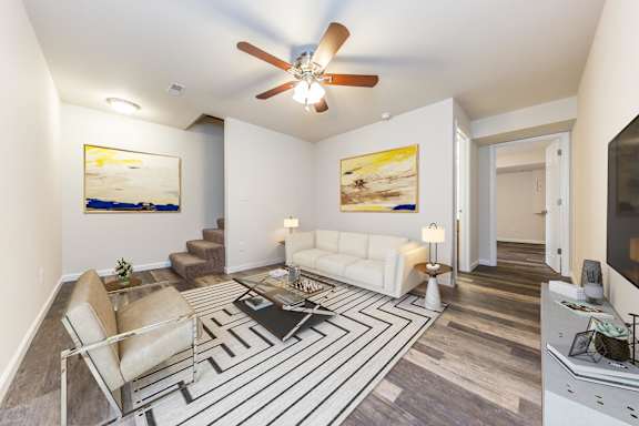 A living room with a striped rug and a ceiling fan.