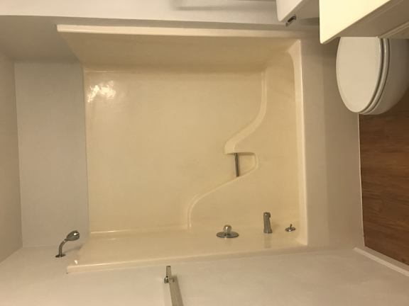 A white bathroom with a white tub and a white toilet.
