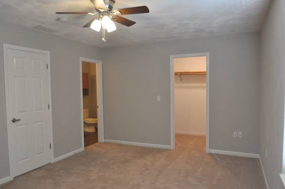 A room with a ceiling fan and carpeted floor.