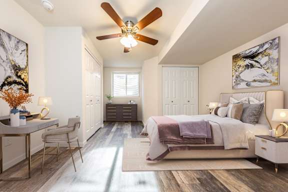 A bedroom with a bed, a table, and a ceiling fan.