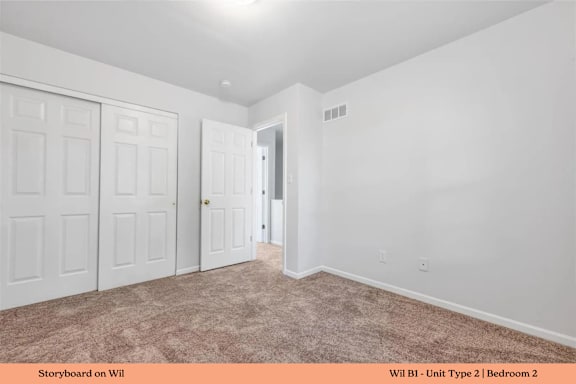 A bedroom with a carpeted floor and two doors.