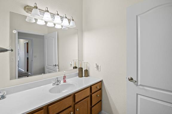 A bathroom with a sink, mirror, and light fixture.