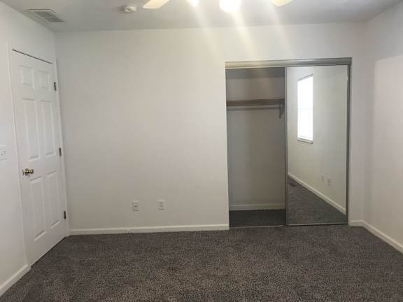 A room with a white door and a grey carpet.