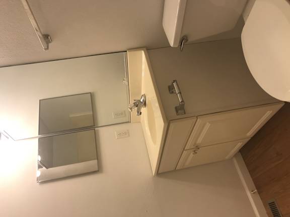 A bathroom with a toilet, sink, and mirror.