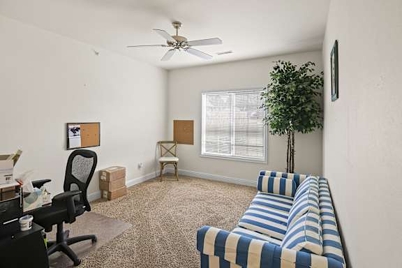 A room with a striped couch and a ceiling fan.
