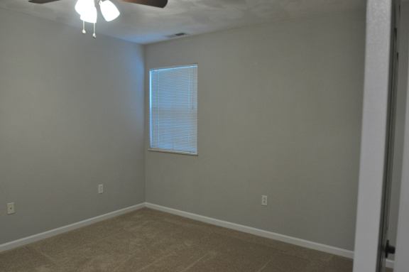 A room with a ceiling fan and a window with blinds.
