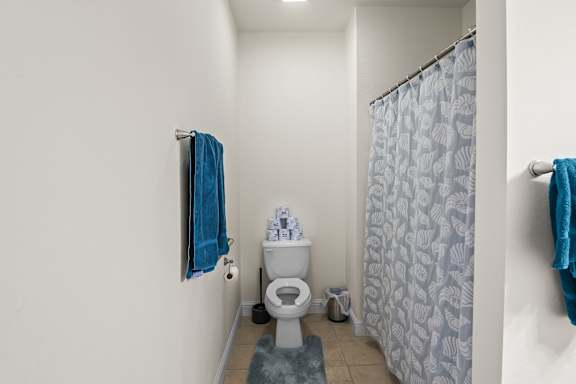 A bathroom with a toilet, a towel, and a shower curtain.